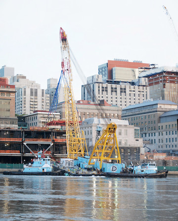 Rockefeller University’s Two-Acre Expansion Sails Up the East River 3 A daytime shot of the crane, with the modules already inserted just ahead of the crane and the FDR Drive at the green fencing level just above the river. | FRANK FARANCE