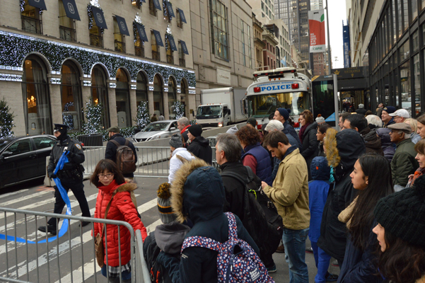 Easing Congestion, 56th Street Reopened West of Trump Tower 1 Pedestrians wait on the northwest corner of 56th Street and Fifth Avenue, in front of the newly relocated police command post protecting Trump Tower across the avenue, while traffic, now resumed on the block between Fifth and Sixth Avenues, turns right onto Fifth. | JACKSON CHEN