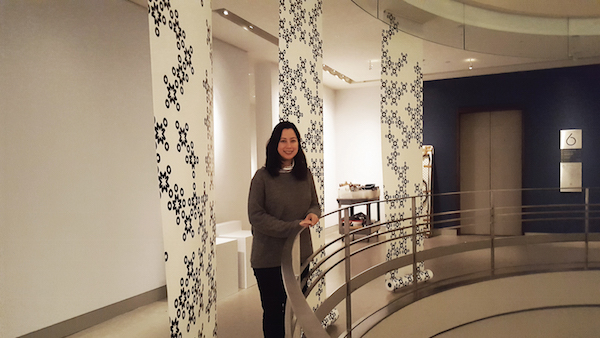Curator Risha Lee stands with banners whose reverse sides give information about the historical and religious context of Om. Photo by Dusica Sue Malesevic. 