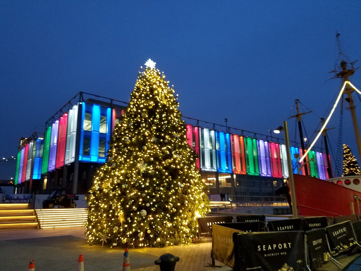 The Seaport Christmas tree in exile, by the docks in front the festively lit Pier 17 building.