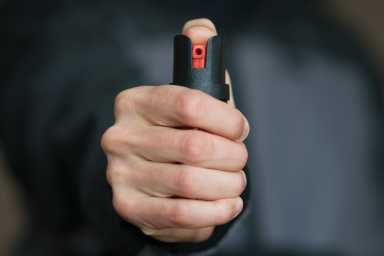 Man holding pepper spray (tear gas) in his hand. Self-defense. Blur background, close up