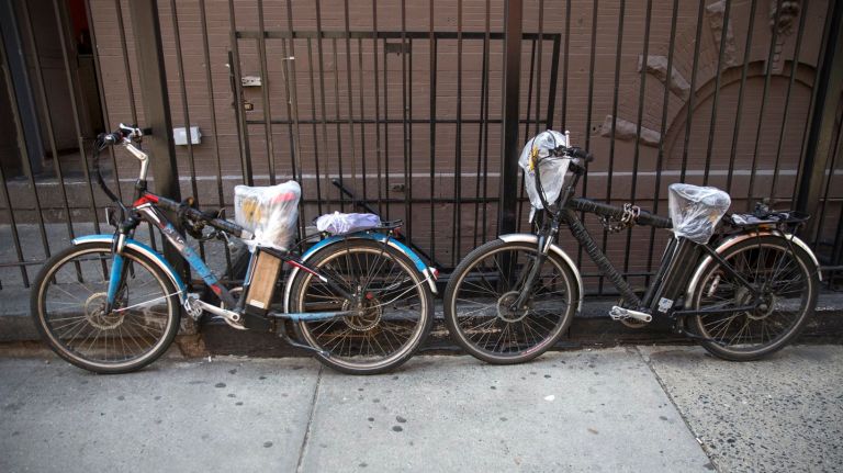 E-bikes stand near a noodle shop on Ninth  Avenue  in Manhattan, on Tuesday, April 11, 2017.