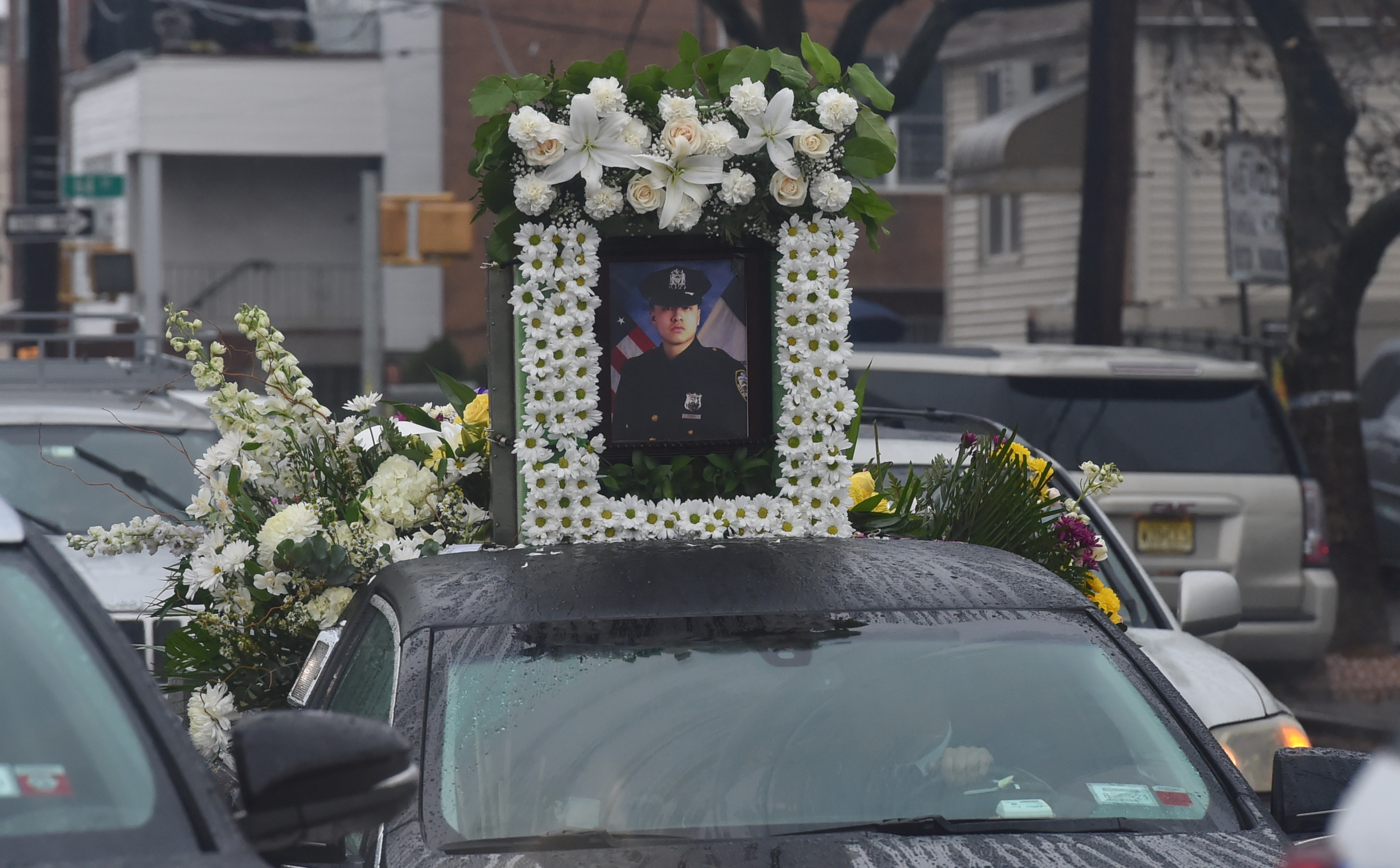 A photo of Police Officer Garman Chen sits atop a hearse at the funeral on 65th Street