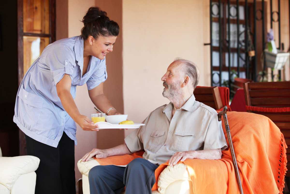 carer bringing meal to senior