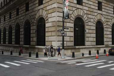 People walk wearing masks outside The Federal Reserve Bank of New York in New York