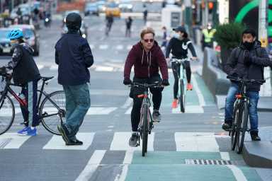 Cyclists ride through Times Square during evening rush hour in New York