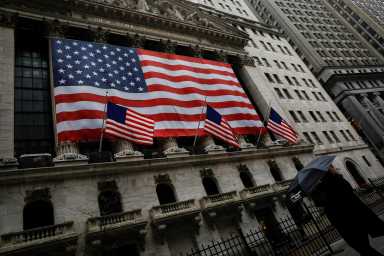 A woman walks in the rain outside the New York Stock Exchange (NYSE) in the financial district of lower Manhattan during outbreak of coronavirus disease (COVID-19) in New York