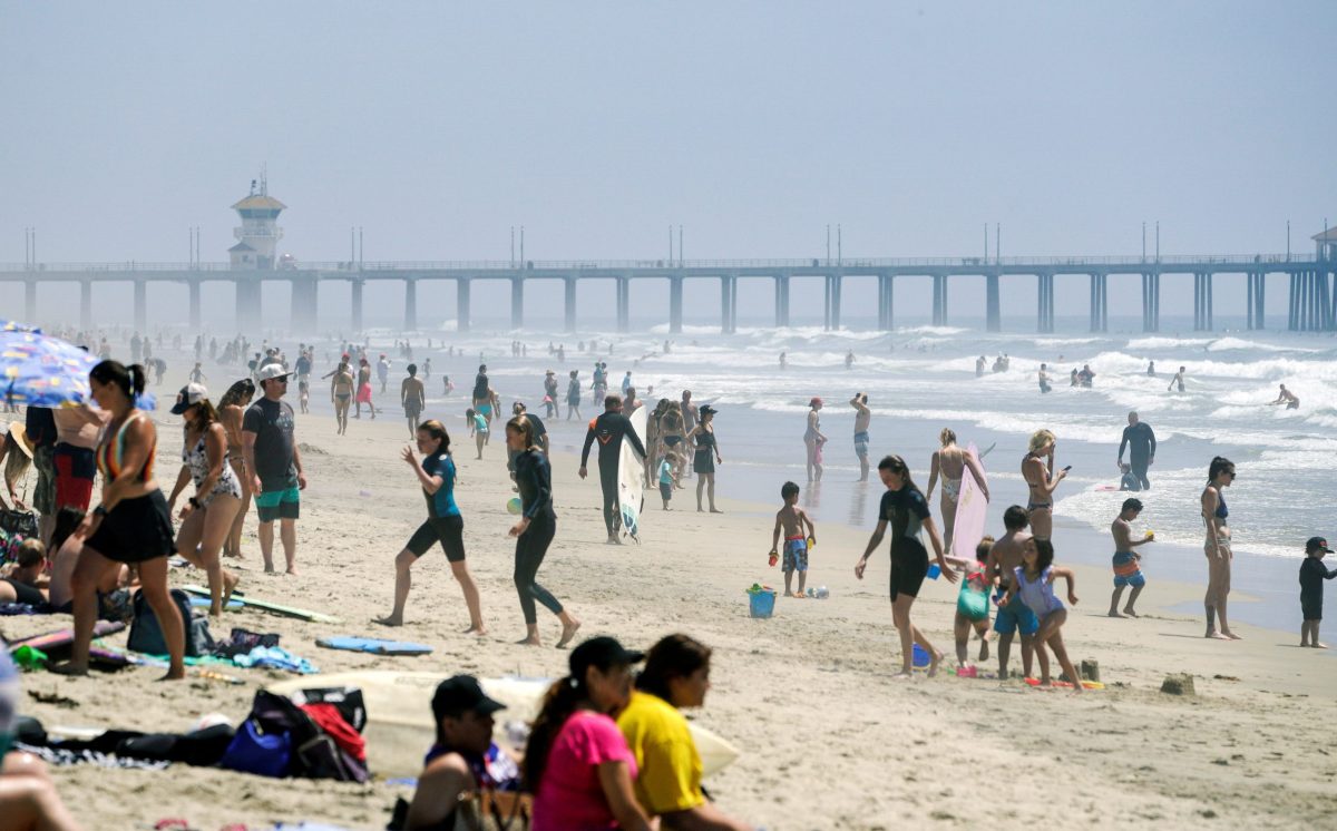 People walk up and down Huntington City Beach during the outbreak of the coronavirus disease (COVID-19), in Huntington Beach