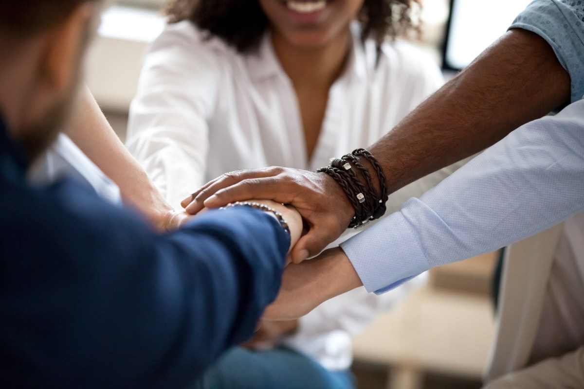 Diverse business people put hands together in pile