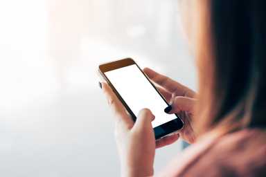 Asian woman using and typing a blank white screen smartphone in airport terminal.