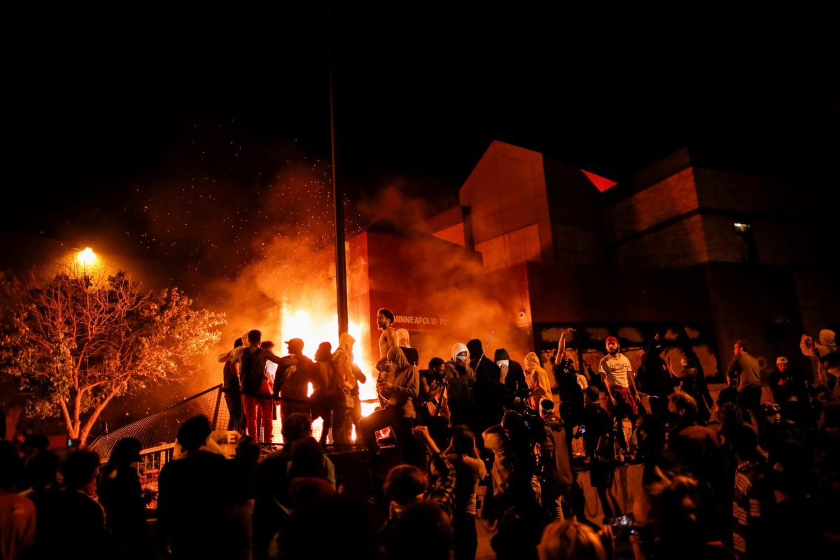 Protesters gather around after setting fire to the entrance of a police station as demonstrations continue in Minneapolis