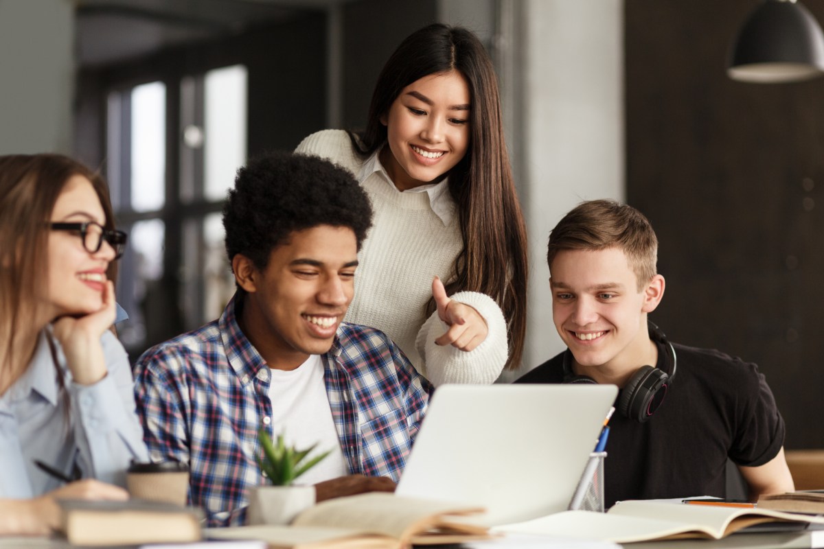 College students using laptop in library, studying together