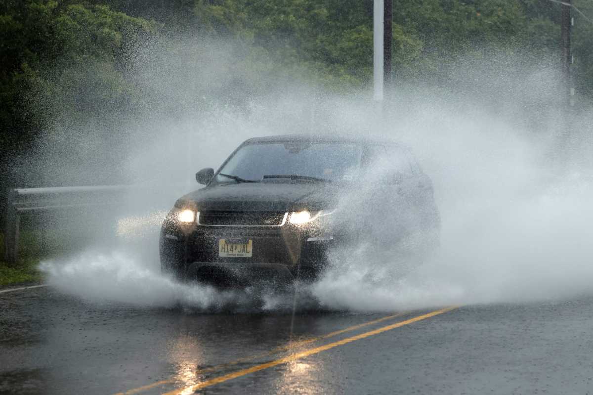 A car moves through a partially flooded street as Tropical Storm Fay sweeps across the heavily populated northeastern United States in Jersey City