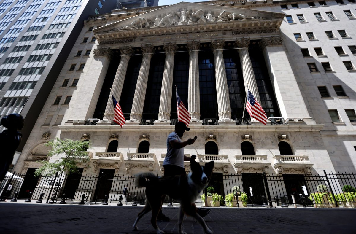 FILE PHOTO: A man walks a dog in the shade past the New York Stock Exchange (NYSE) during hot weather in New York