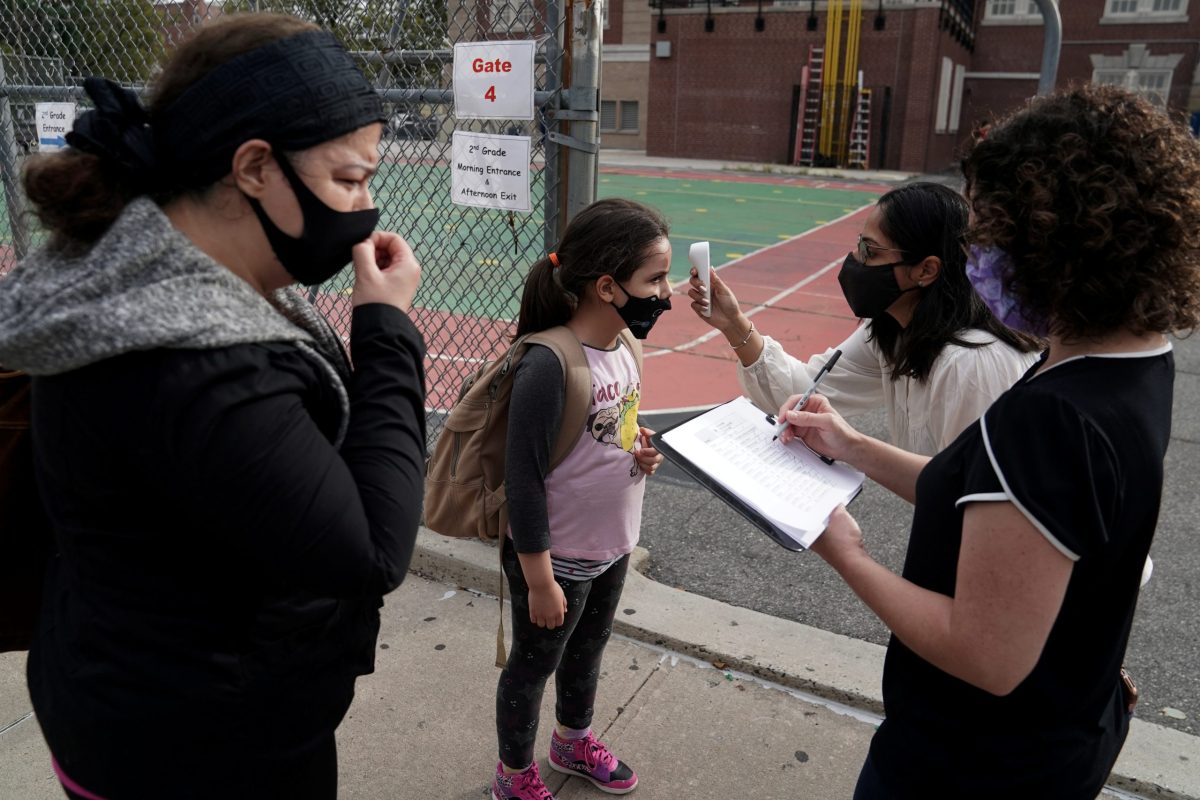 A child has her temperature taken before attending the first day of grade 2