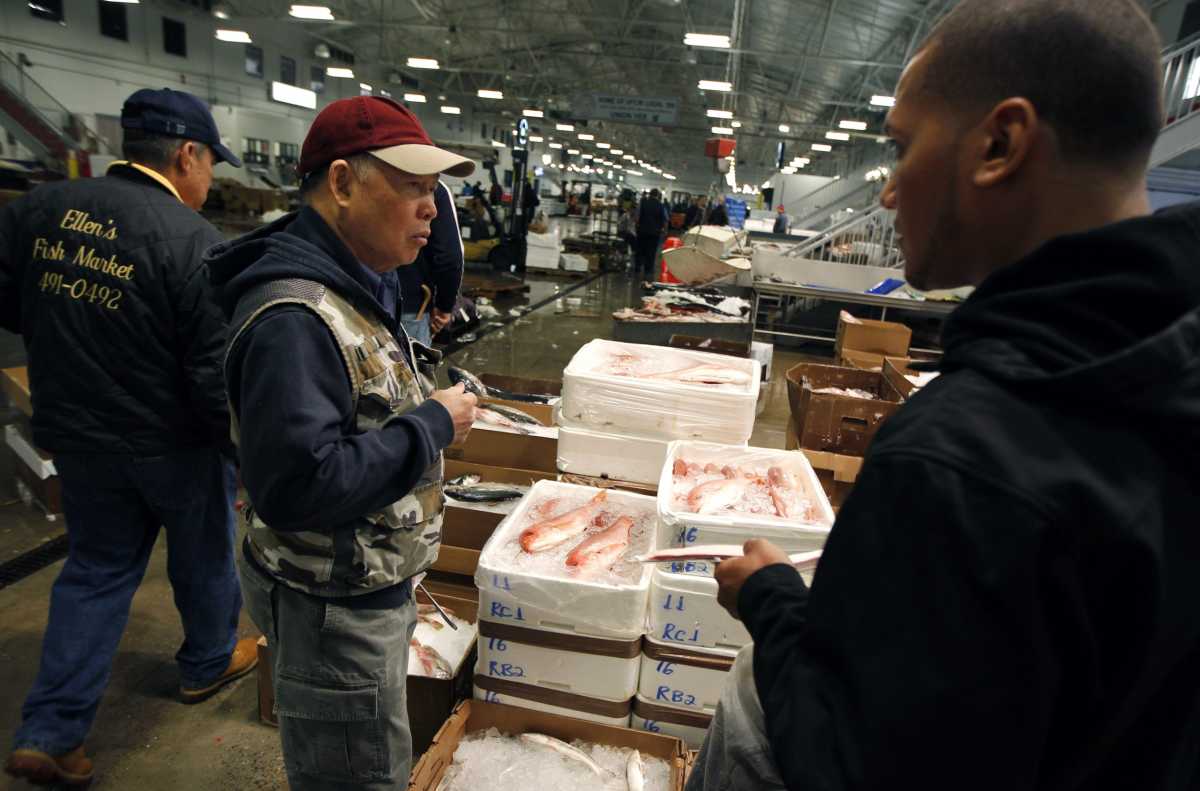 A customer buys red snapper at JMS Seafood