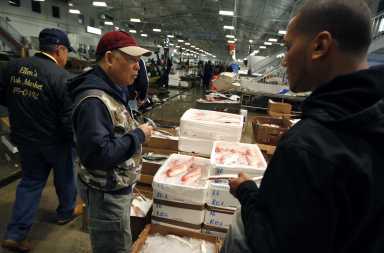A customer buys red snapper at JMS Seafood