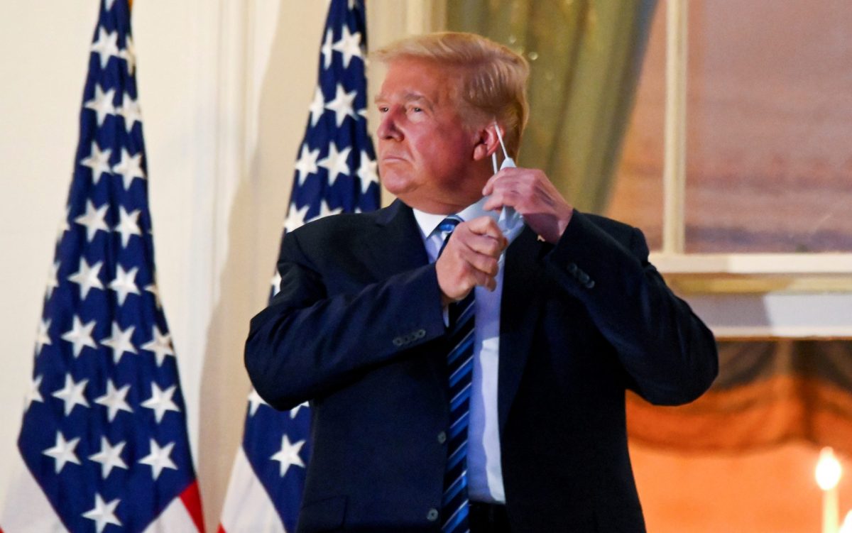 FILE PHOTO: U.S. President Donald Trump pulls off his face mask as he returns to the White House after being hospitalized at Walter Reed Medical Center for coronavirus disease (COVID-19)