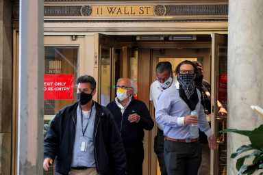 Traders exit the 11 Wall St. door of the NYSE in New York