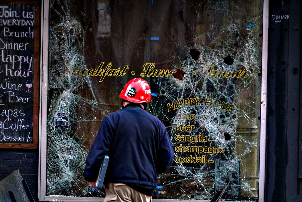 A firefighter examines the fractured windowpane of Café Mocha