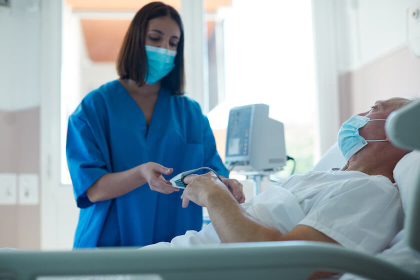 One female nurse measuring a patient’s pulse.