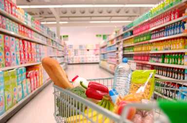 Supermarket trolley filled with vegetables in aisle