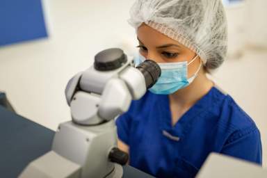 Scientist woman analyzing covid 19 sample with microscope