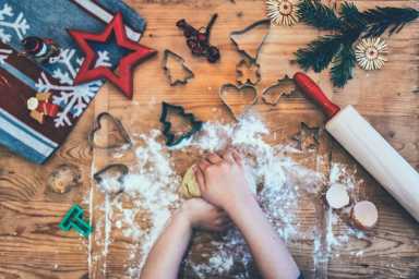 childs hands kneading christmas cookies dough on wooden board