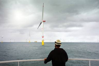 Manual worker offshore looking on wind-turbines wind farm from boat in North sea close to Borkum