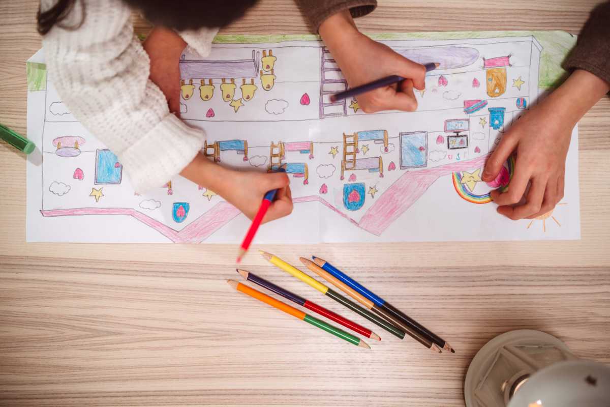 Directly above view of lovely little sister drawing and creating artwork together at home