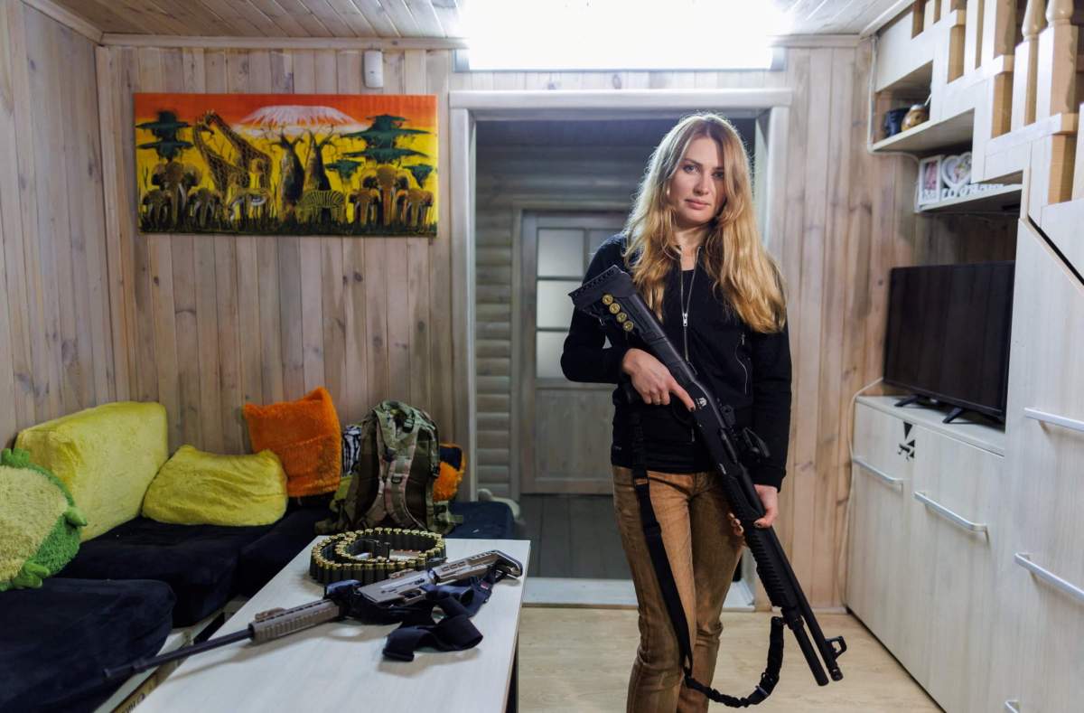 Alisa, a media relations specialist, poses with a gun for a picture at her home near Kyiv