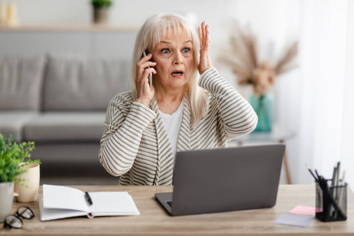 Surprised shocked mature woman talking on mobile phone