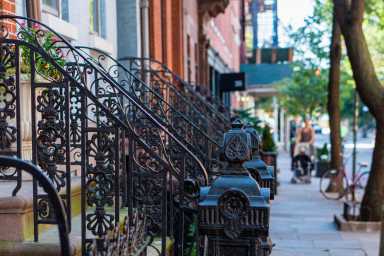 Classic red brick brownstone buildings with black iron railings in Greenwich Villages, Manhattan, New York Citty. Street scene