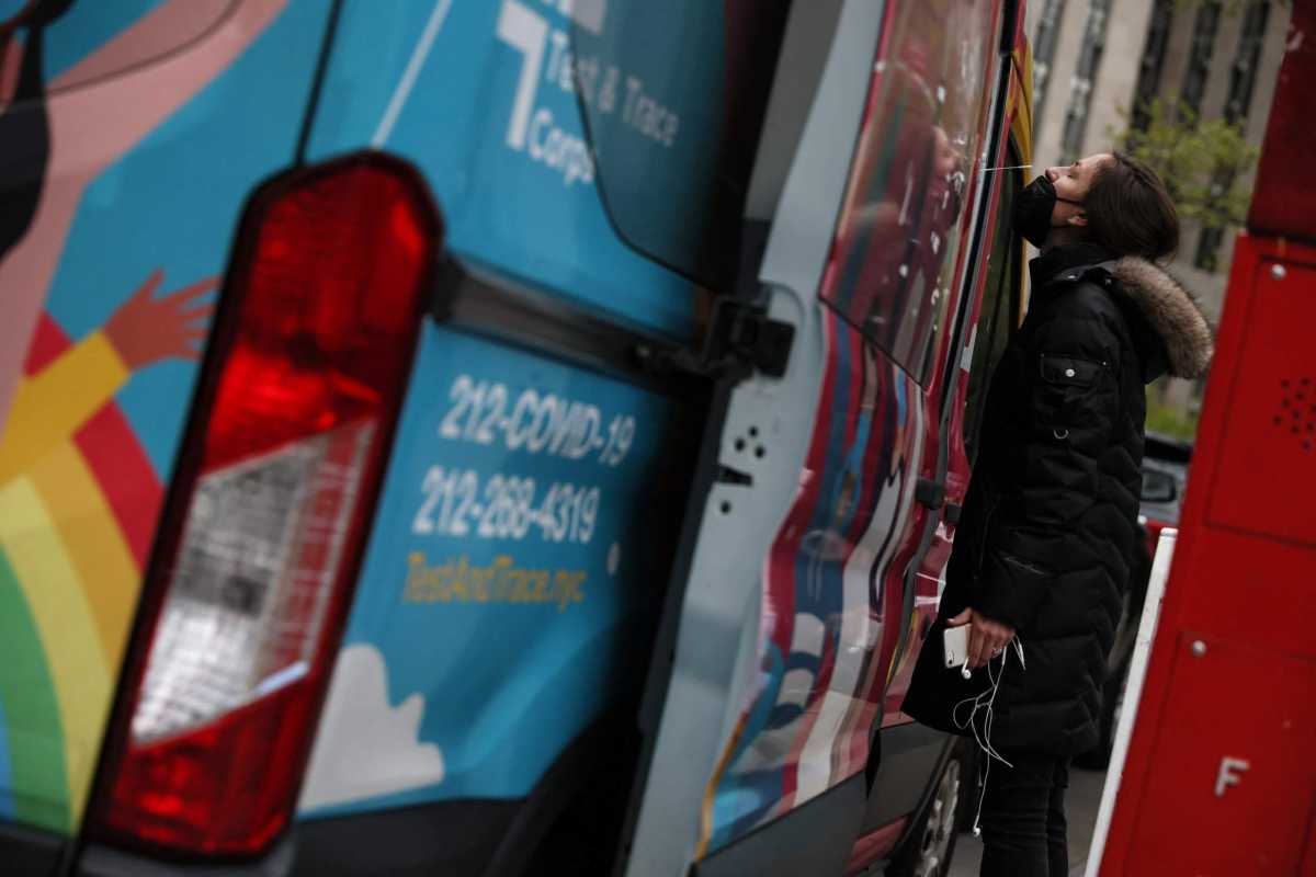 A health care worker administers a testing swab to a woman at a mobile coronavirus disease (COVID-19) testing center in New York City