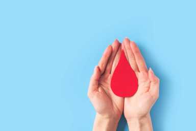 World hemophilia day concept with red blood drop simbol and hands on blue background
