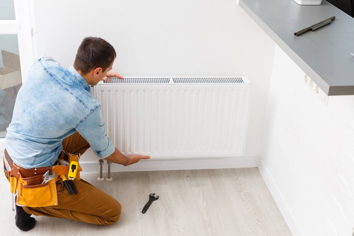 Man is repairing radiator battery in the room. Maintenance repair works renovation in the flat. Heating restoration. Wrench in hands.