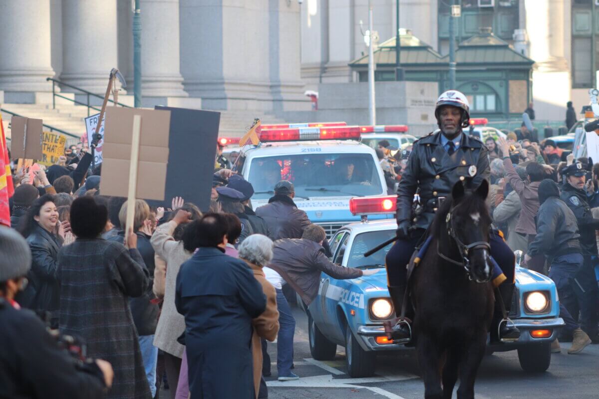 Crowds descend on a police van holding the Joker, on the set of Joker 2, "Joker: Folie à Deux" (Photo by Michael Dorgan)