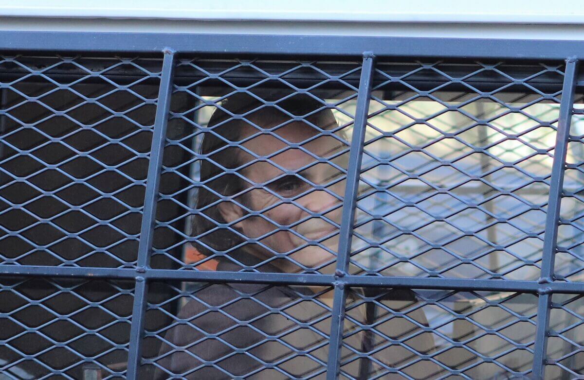 Joaquin Phoenix, playing Joker, smiles from a police van on the set of Joker 2, "Joker: Folie à Deux" (Photo by Michael Dorgan)
