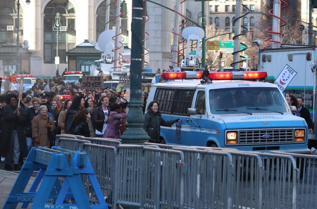Crowds descend on a police van holding the Joker, on the set of Joker 2, "Joker: Folie à Deux" (Photo by Michael Dorgan)