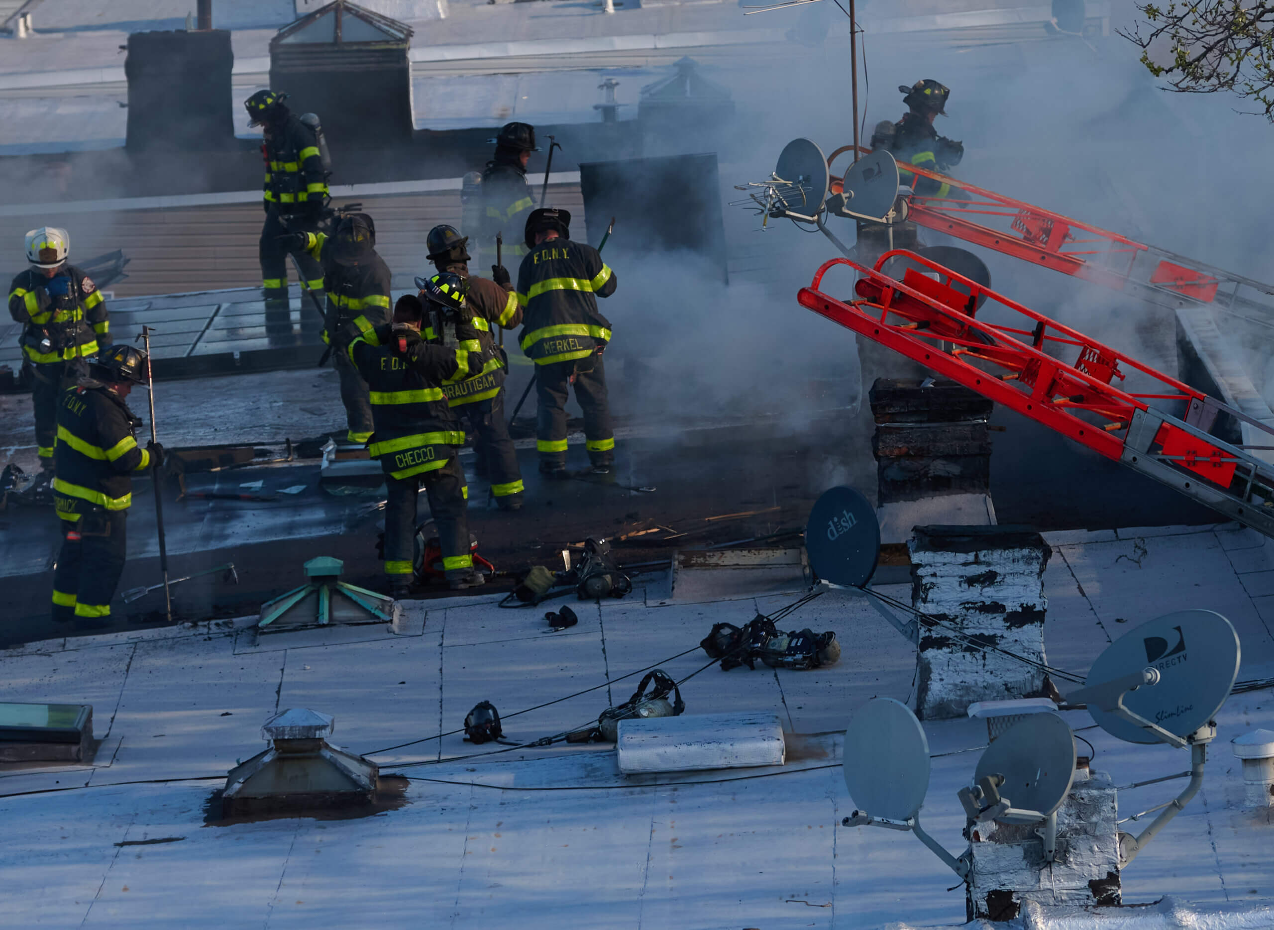 Firefighters work to cut holes in the roof during a two alarm fire at 82 Nicholas Avenue in Cypress Hills