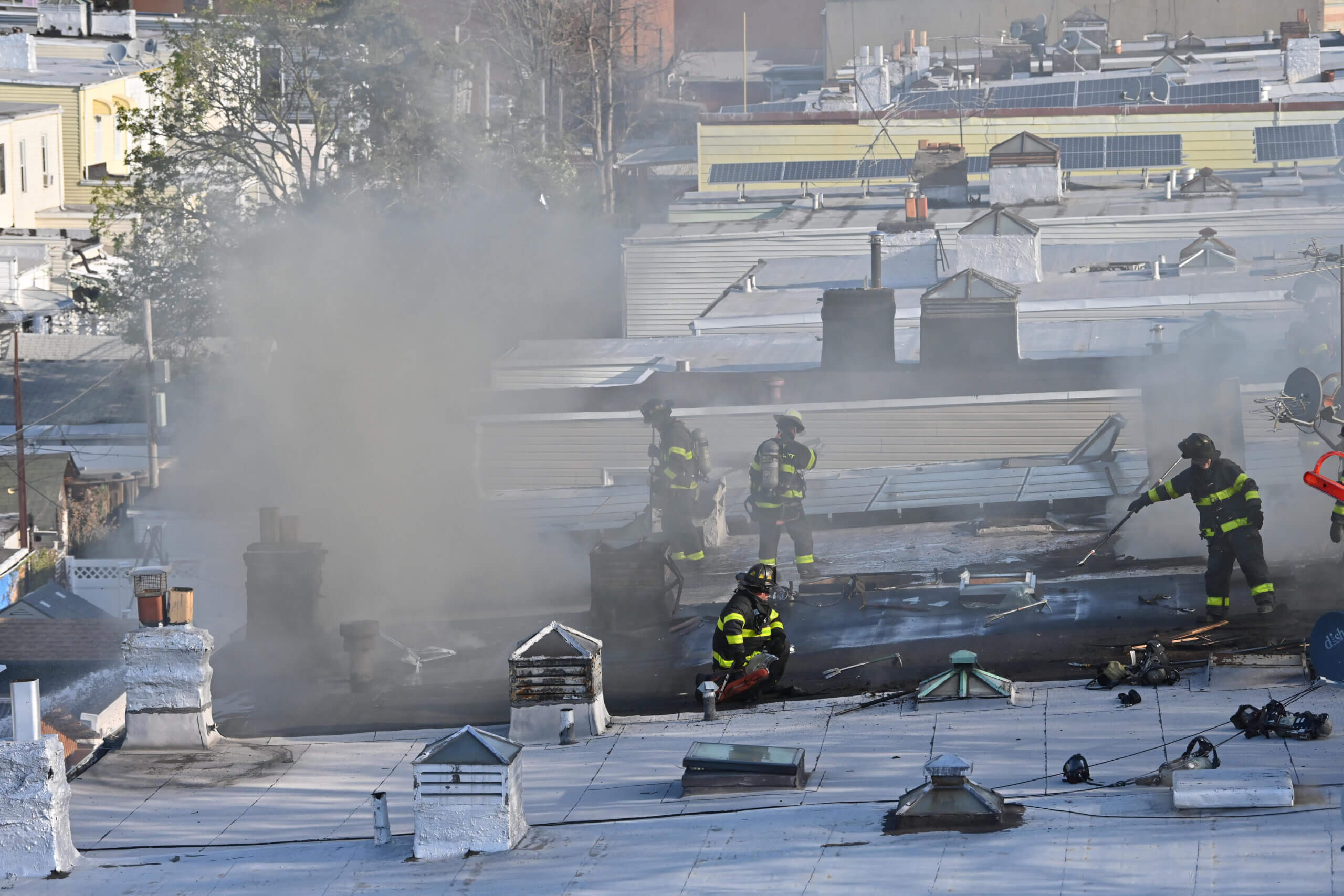 Firefighters work to cut holes in the roof during a two alarm fire at 82 Nicholas Avenue in Cypress Hills