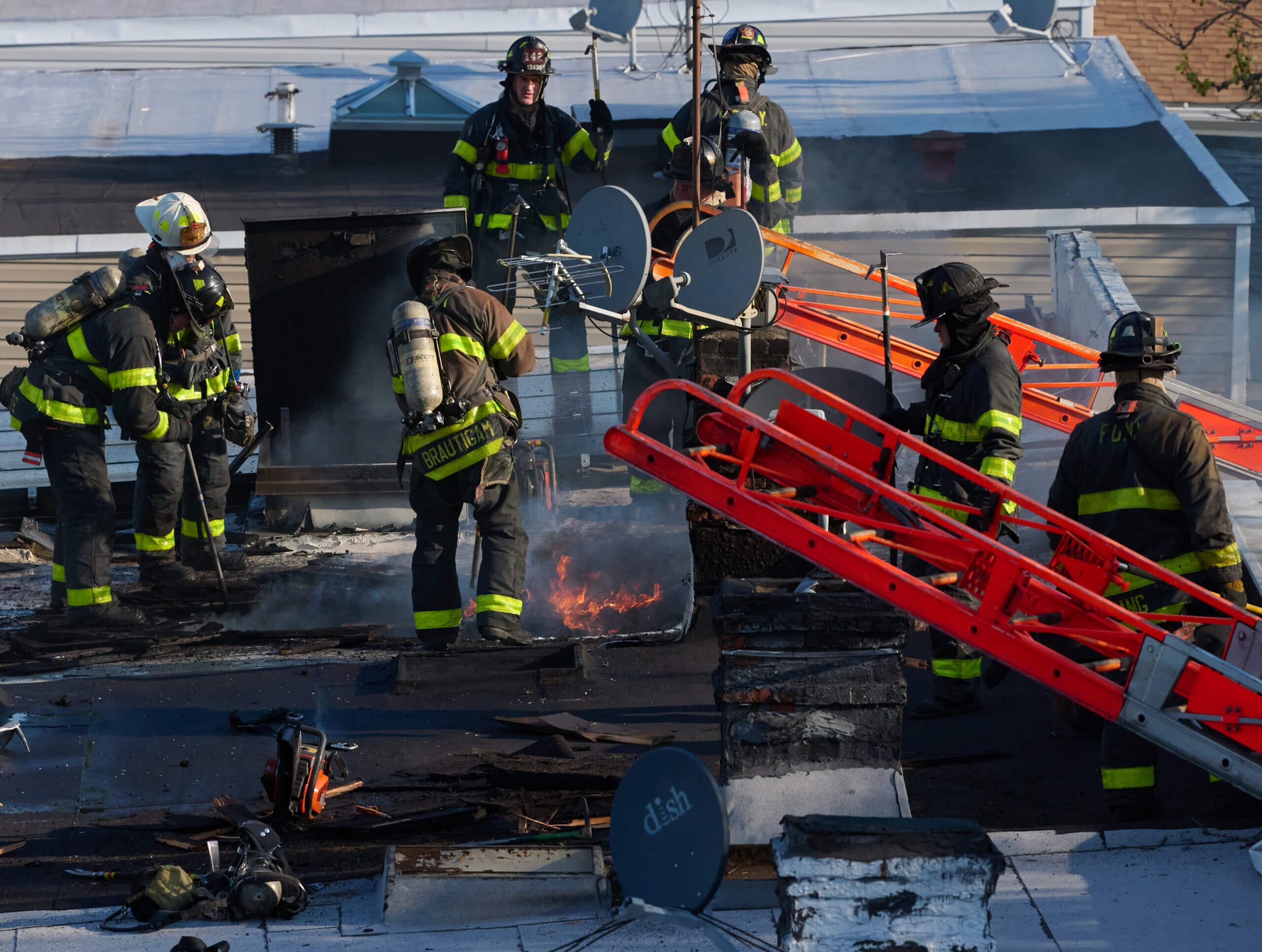 Firefighters work to cut holes in the roof during a two alarm fire at 82 Nicholas Avenue in Cypress Hills