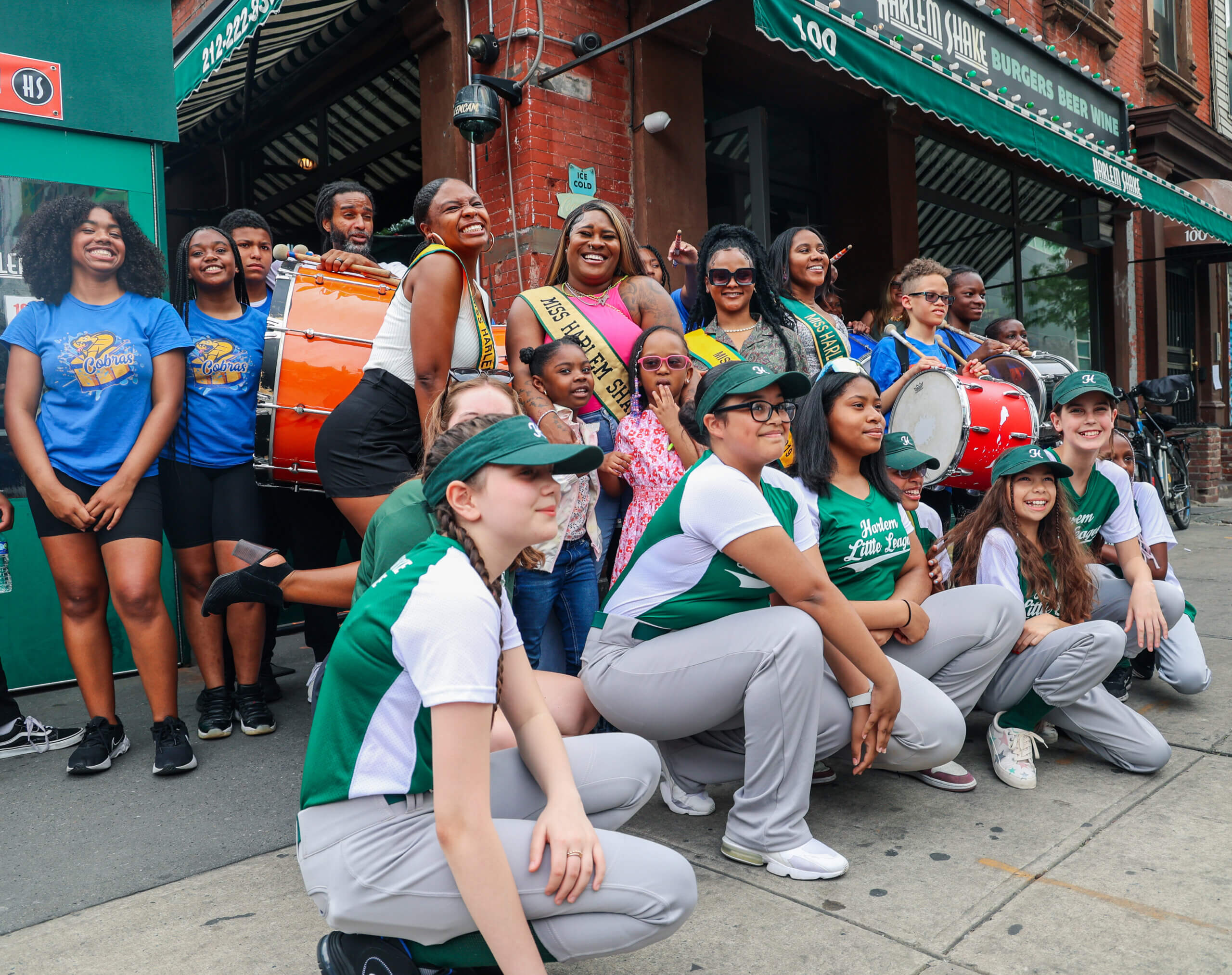 The Marching Cobras, Harlem Little League, and former Miss Harlem Shake winners in front of the Harlem Shake flagship location for its 10th Anniversary