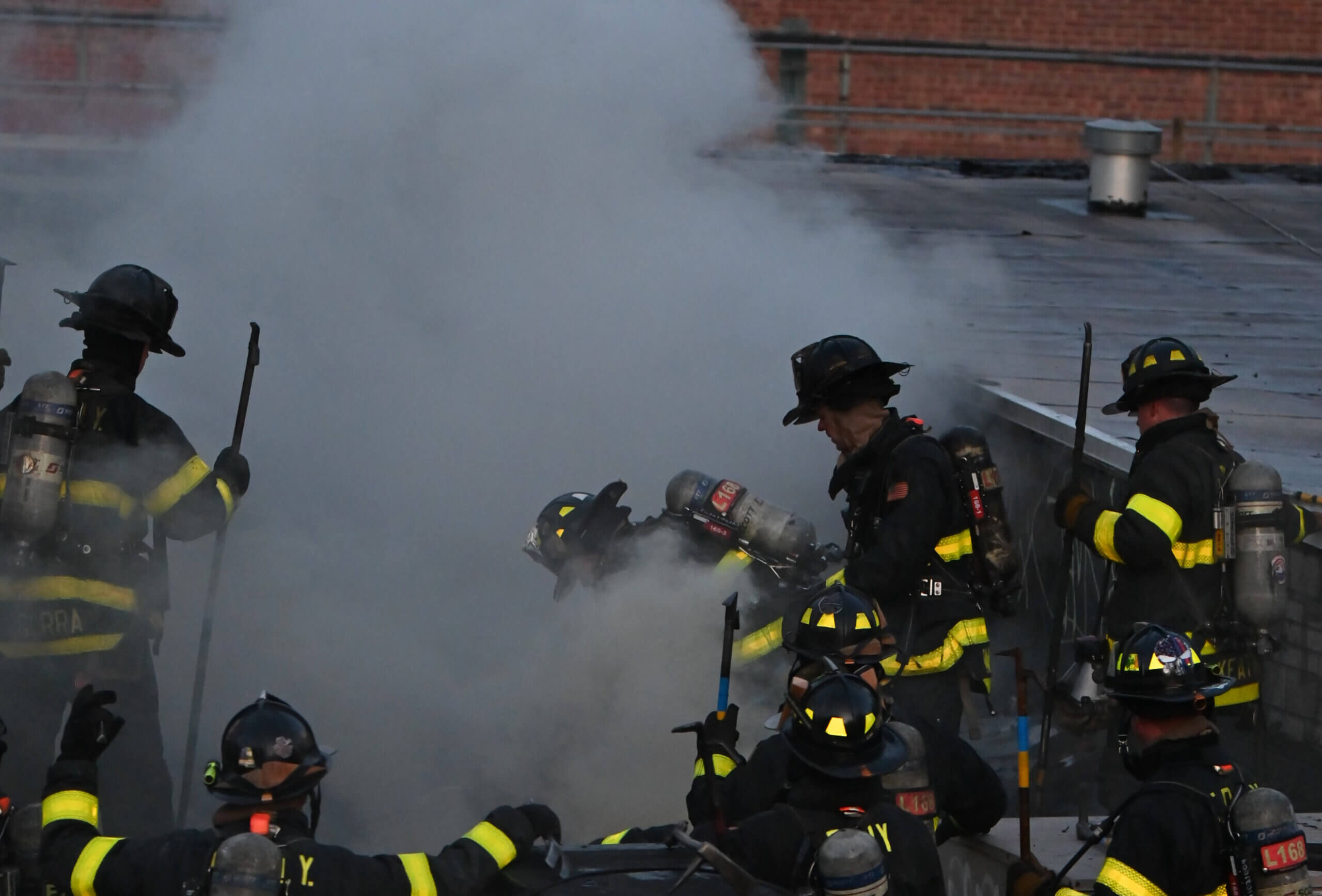 A firefighter cuts a hole while working in a heavy smoke condition during a four alarm fire at Paradise Manor at 5802 New Utrecht Avenue on Tuesday evening