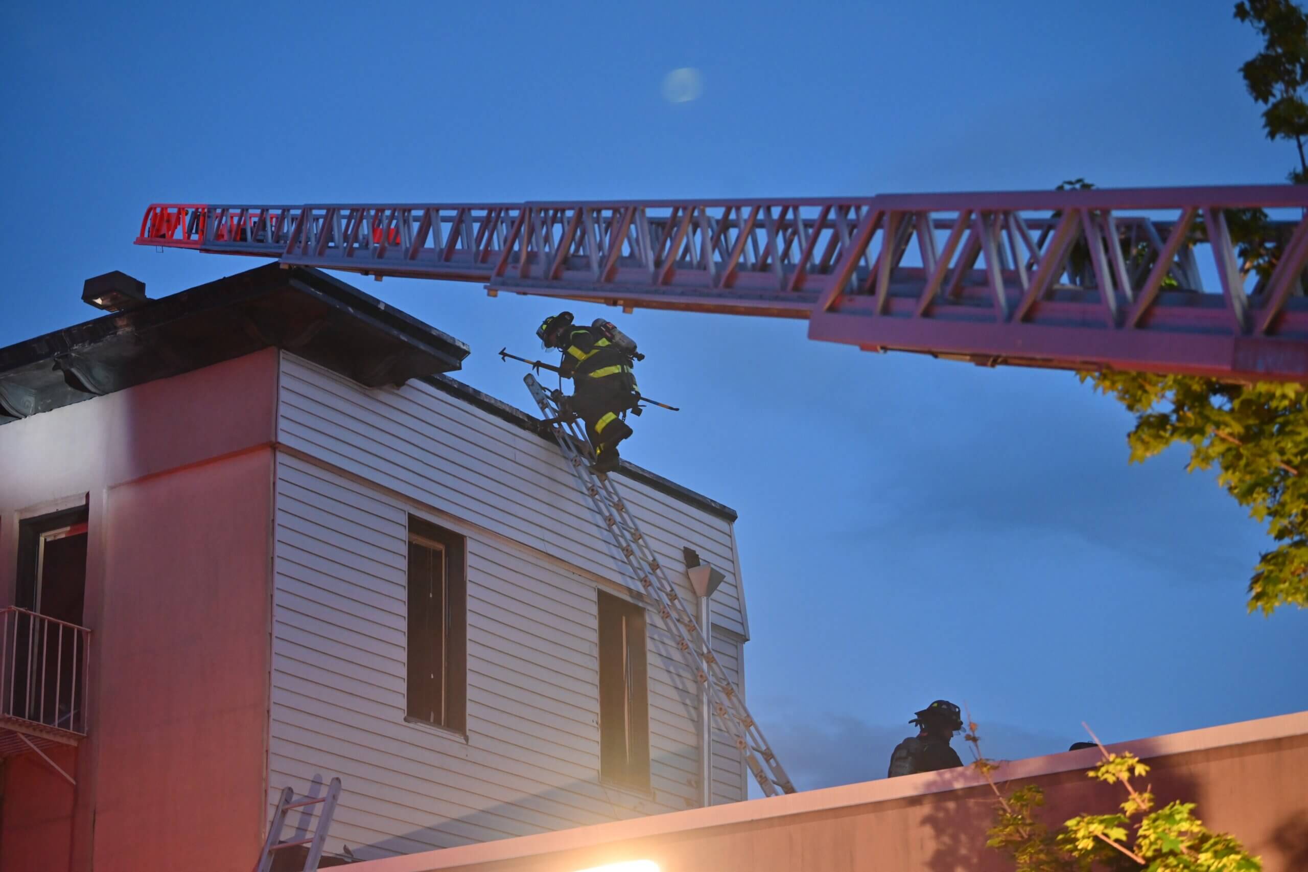 A firefighter cuts a hole while working in a heavy smoke condition during a four alarm fire at Paradise Manor at 5802 New Utrecht Avenue on Tuesday evening