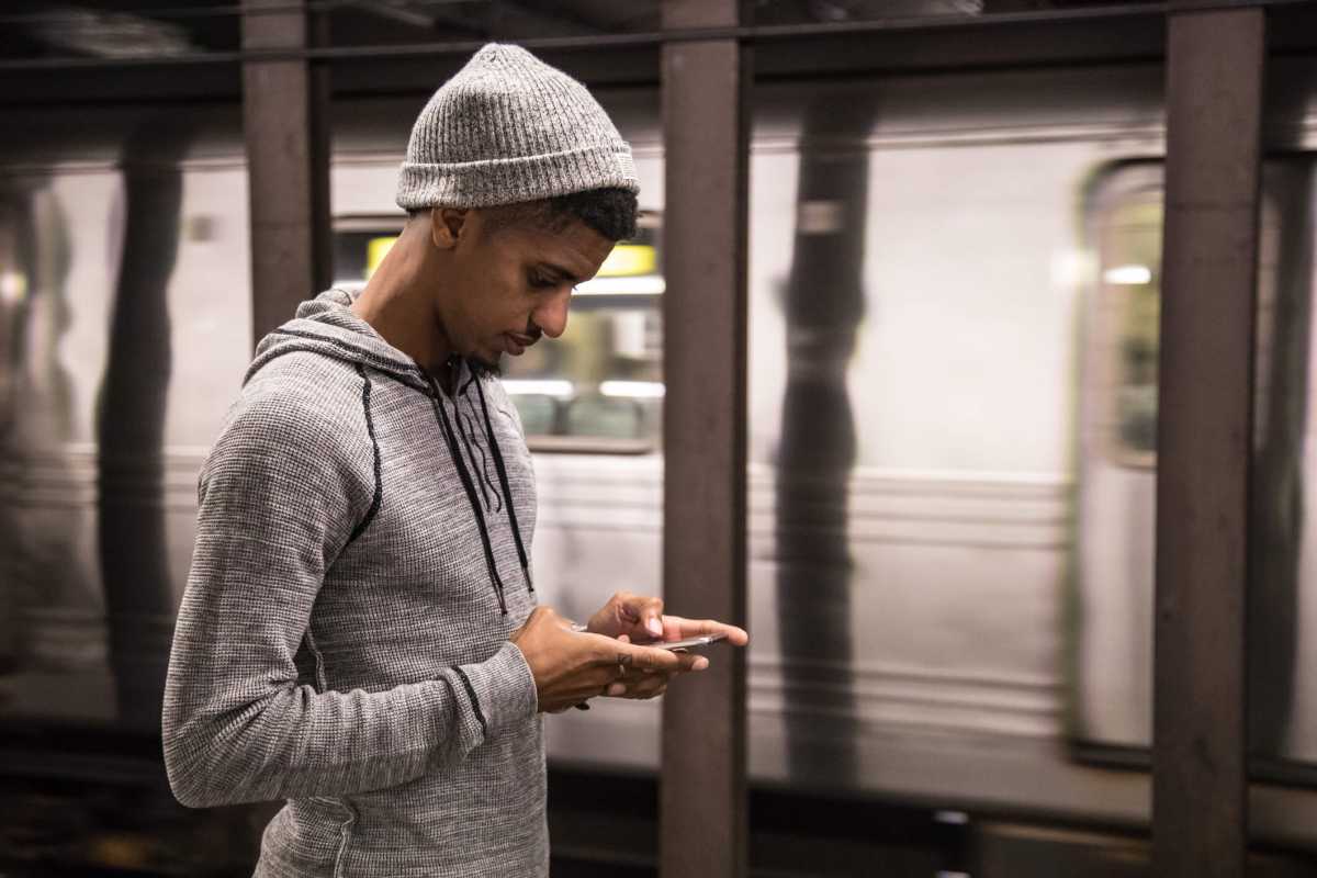 A man looking at his phone on a subway platform.