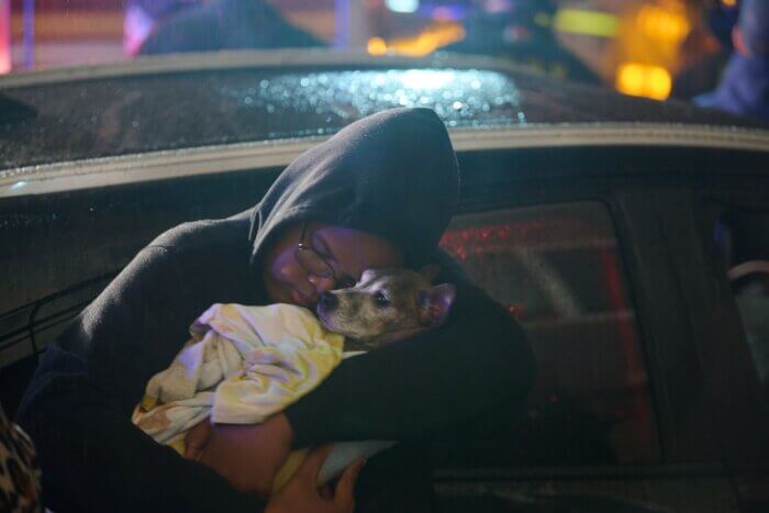 A resident cradles her dog as firefighters work to knock down the blaze