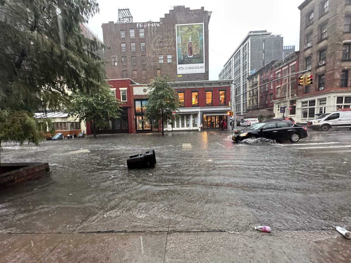 A vehicle travels through the flooded stretch of West Broadway and Grand Street in Soho.