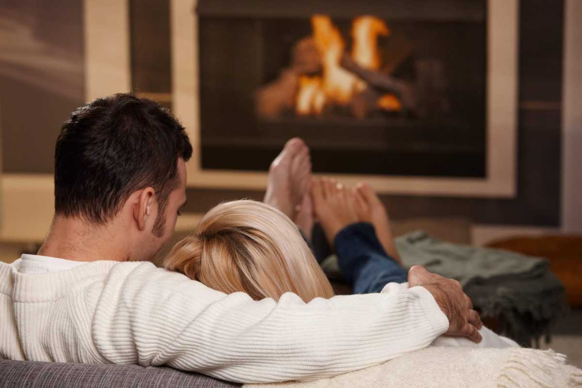 A man and woman sitting in front of a fire, like couples would during cuffing season.