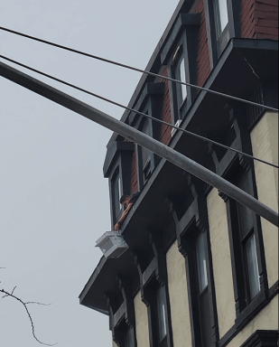 A man holding a falling air conditioner from a NYC building window